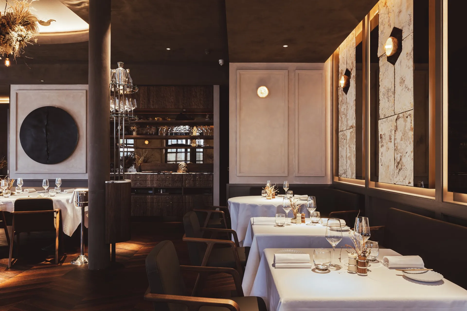 The Ledbury dining room in London with glowing mycelium wall panels, timber, and set tables